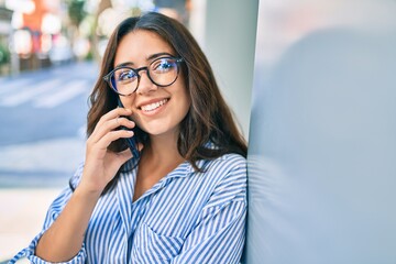 Young hispanic businesswoman smiling happy talking on the smartphone at the city.