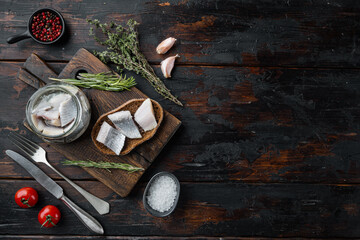 Canned Herring , fish preserves, on wooden cutting board, on old dark  wooden table background. with herbs and ingredients, top view flat lay, with copyspace  and space for text