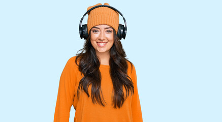 Beautiful brunette young woman listening to music using headphones with a happy and cool smile on face. lucky person.