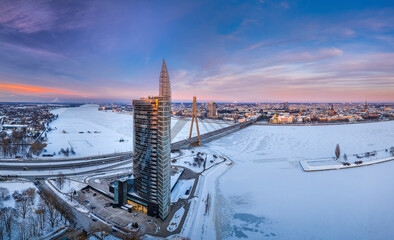 Riga city panorama at colorful sunset in blue hour. Modern skyscrapers next to picturesque view...