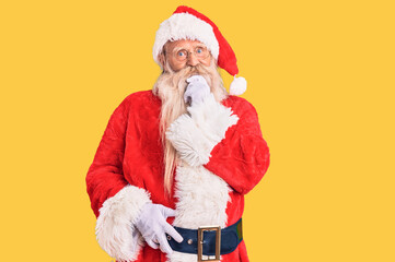 Old senior man with grey hair and long beard wearing traditional santa claus costume looking confident at the camera smiling with crossed arms and hand raised on chin. thinking positive.