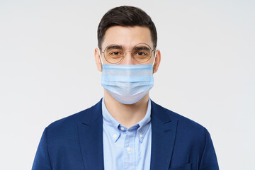 Young business man wearing medical mask, standing isolated on gray background