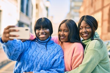 Three african american friends smiling happy making selfie by the smartphone at the city.