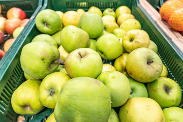 A variety of green apples on the counter in the supermarket. Healthy eating and vegetarianism. Side view.