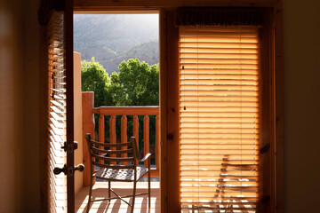 Good morning. Open door to a balcony with a chair and a view bathed in the morning sun. Nobody.