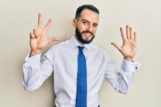 Young man with beard wearing business tie showing and pointing up with fingers number eight while smiling confident and happy.