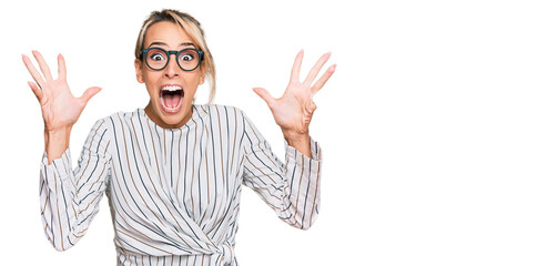Beautiful blonde woman wearing business shirt and glasses celebrating crazy and amazed for success...