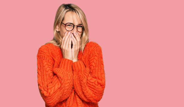Beautiful blonde woman wearing casual clothes and glasses laughing and embarrassed giggle covering mouth with hands, gossip and scandal concept