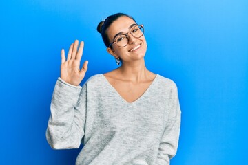 Young hispanic woman wearing casual clothes waiving saying hello happy and smiling, friendly welcome gesture © Krakenimages.com