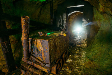 Dirty abandoned uranium mine with rusty rail and trolley