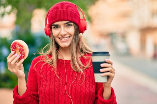 Young hispanic woman having breakfast using headphones at the city.