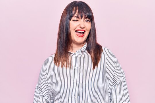 Young plus size woman wearing casual clothes winking looking at the camera with sexy expression, cheerful and happy face.