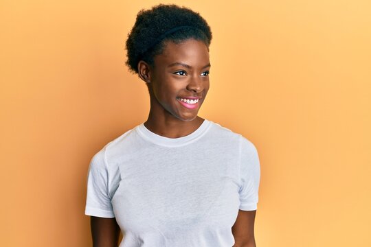 Young African American Girl Wearing Casual White T Shirt Looking To Side, Relax Profile Pose With Natural Face And Confident Smile.