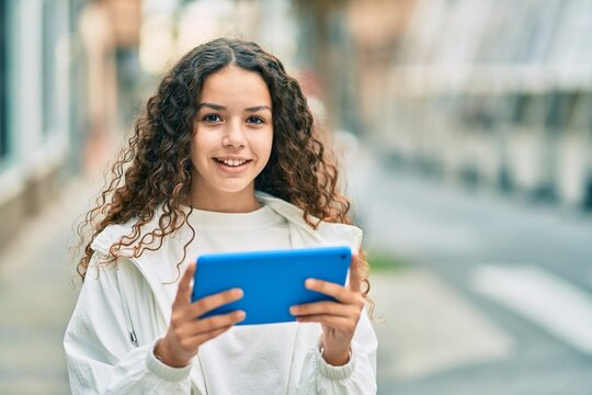 Hispanic teenager girl smiling happy using touchpad at the city.