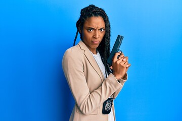 African american police woman holding gun skeptic and nervous, frowning upset because of problem....