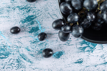 Bowl of black fresh grapes on colorful background
