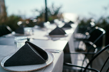 Table in restaurant with sea view. Close up of the napkin in the plate.