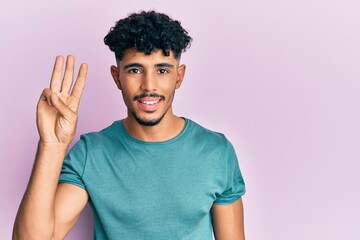 Fototapeta na wymiar Young arab handsome man wearing casual clothes showing and pointing up with fingers number three while smiling confident and happy.