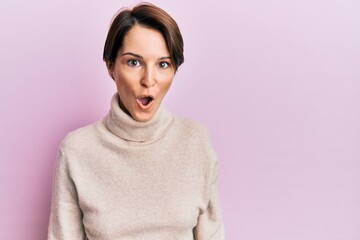 Young brunette woman with short hair wearing casual winter sweater afraid and shocked with surprise expression, fear and excited face.