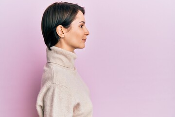Young brunette woman with short hair wearing casual winter sweater looking to side, relax profile pose with natural face with confident smile.