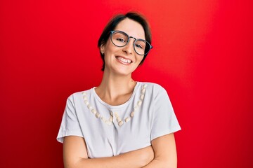 Young brunette woman with short hair wearing casual clothes and glasses happy face smiling with crossed arms looking at the camera. positive person.