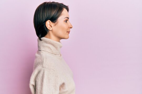 Young Brunette Woman With Short Hair Wearing Casual Winter Sweater Looking To Side, Relax Profile Pose With Natural Face With Confident Smile.