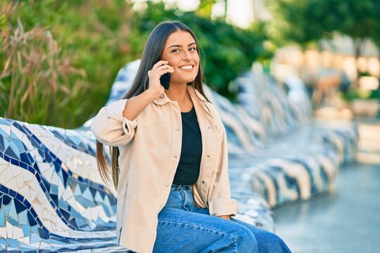 Young hispanic girl smiling happy talking on the smartphone at the park.