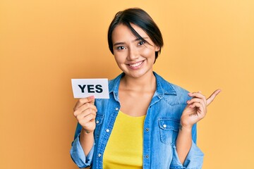 Beautiful young woman with short hair holding yes reminder smiling happy pointing with hand and...