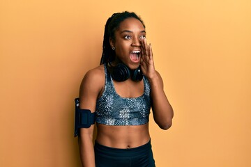 African american woman with braided hair wearing sportswear and arm band shouting and screaming loud to side with hand on mouth. communication concept.