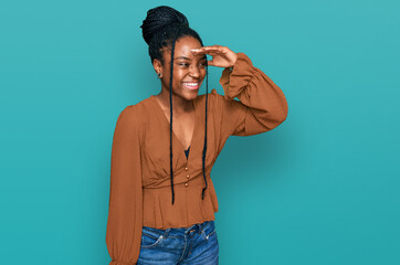 Young african american woman wearing casual clothes very happy and smiling looking far away with hand over head. searching concept.