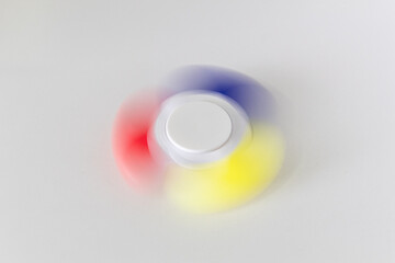 Yellow, blue and red fidget spinner spinning on a white background