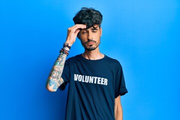 Young hispanic man wearing volunteer t shirt worried and stressed about a problem with hand on...