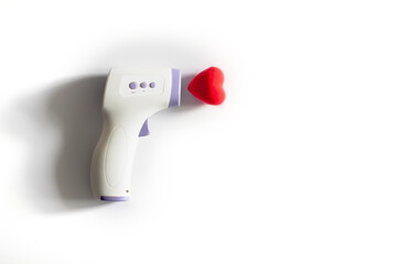 infrared contactless thermometer next to voluminous heart on white background with trend shadows....