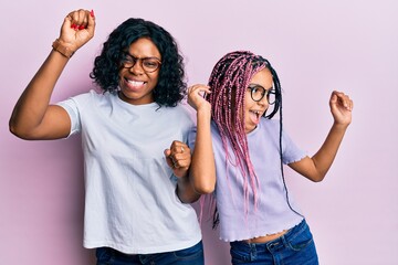 Beautiful african american mother and daughter wearing casual clothes and glasses dancing happy and cheerful, smiling moving casual and confident listening to music