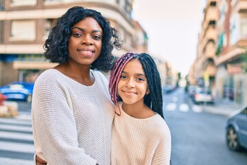 Beautiful african american mother and daughter smiling happy and hugging. Standing with smile on face standing at the city.