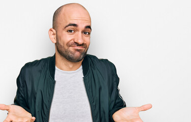 Young hispanic man wearing casual clothes clueless and confused expression with arms and hands...