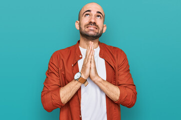 Young hispanic man wearing casual clothes begging and praying with hands together with hope...