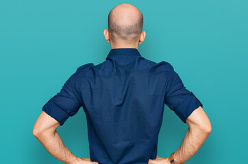 Young hispanic man wearing casual clothes standing backwards looking away with arms on body