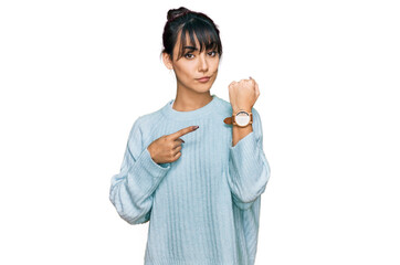Young hispanic woman wearing casual clothes in hurry pointing to watch time, impatience, looking at...