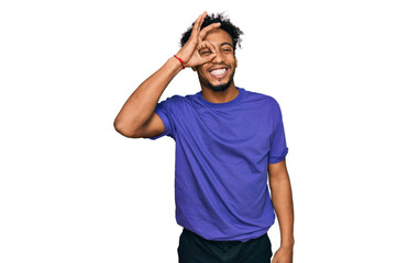 Young african american man with beard wearing casual purple t shirt doing ok gesture with hand smiling, eye looking through fingers with happy face.