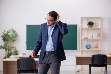 Young male teacher in front of green board