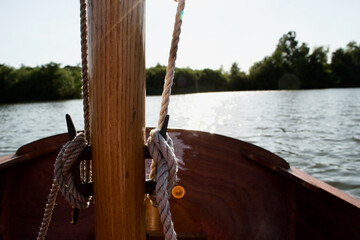 Close up of the cleats on the wooden mast of a small sailing boat (dinghy): ropes (halyards) tied...