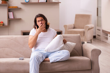 Obraz premium Young lazy man in oversleeping concept at home