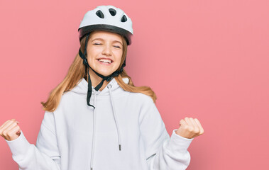 Beautiful young caucasian girl wearing bike helmet very happy and excited doing winner gesture with arms raised, smiling and screaming for success. celebration concept.