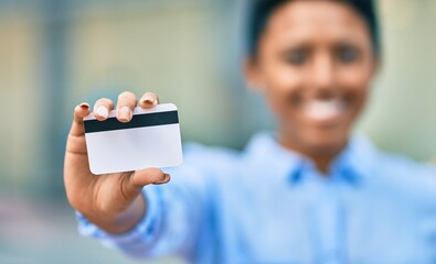 Young african american girl smiling happy holding credit card at the city.