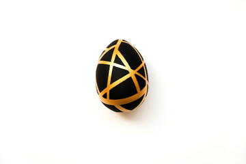 Easter golden egg with geometric black pattern isolated on white background. Minimal easter concept. Happy Easter card with copy space for text. Concept for banner, flyer, invitation, greeting card.