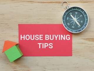 Selective focus on image of compass with a piece of red paper  written HOUSE BUYING TIPS and house...
