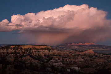 Naklejka na ściany i meble dramatic landscape photo of Bryce Canyon.gigantic cumulonimbus desert storm cloud passing through the hoodoos of the Bryce Canyon National Park just right after sunset.