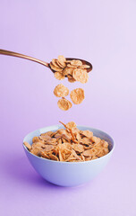 Bowl with tasty cornflakes and spoon on color background