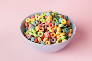 Bowl with tasty cereal rings on color background